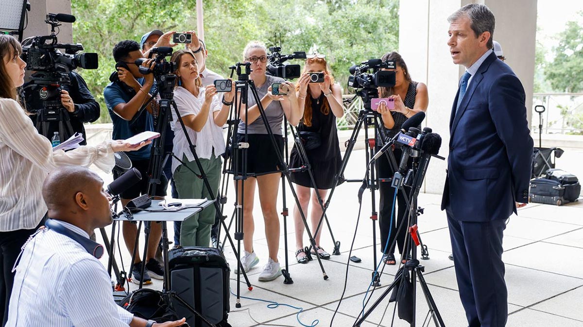David Oscar Markus stands in front of the courthouse giving a press conference to several members of the press.
